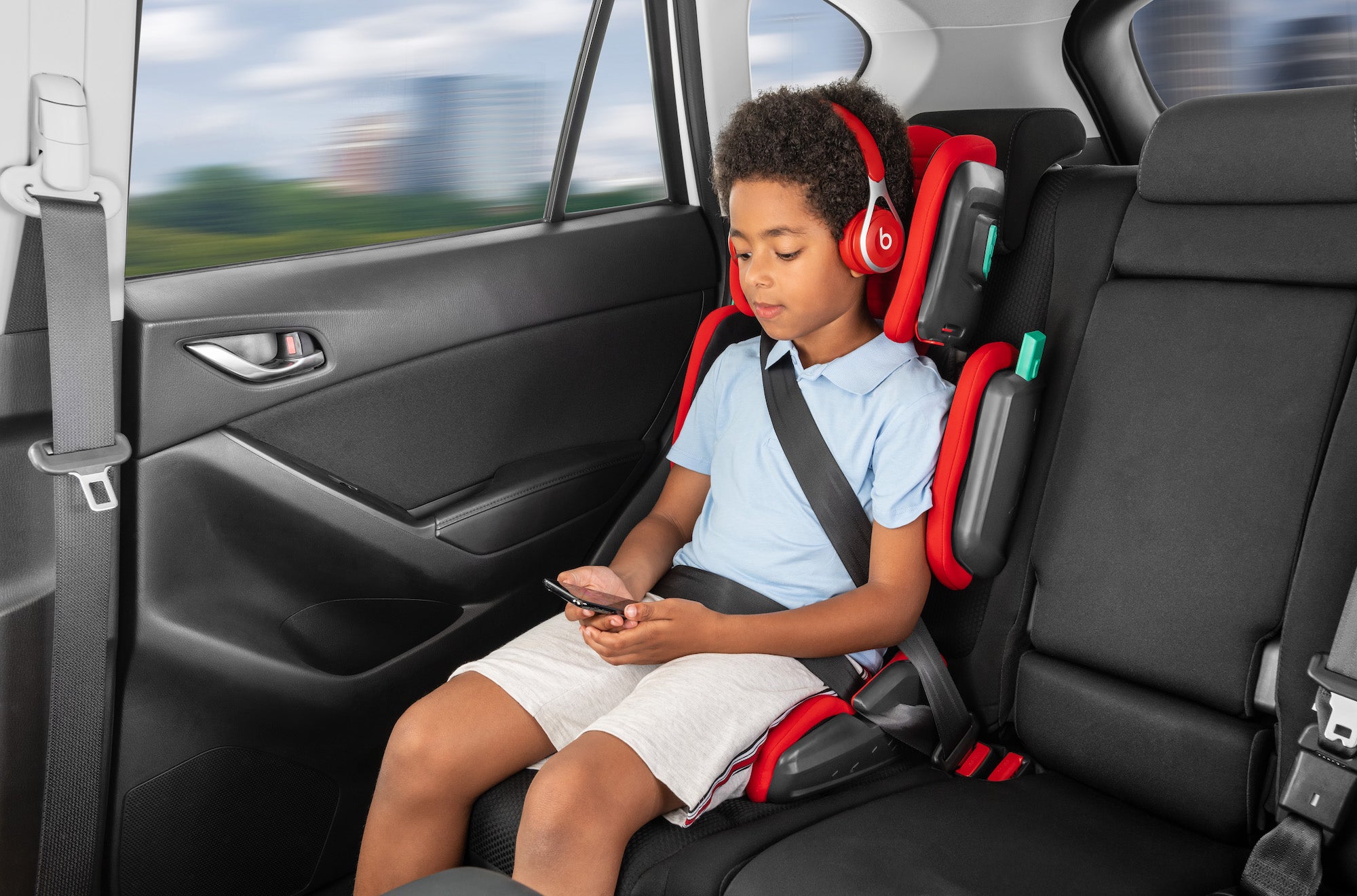 Older boy sitting on a hifold highback booster in the car